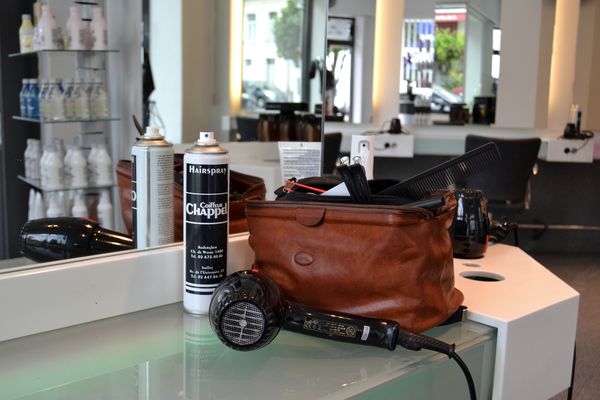 Sèche-cheveux, laque et trousse posés sur un poste de coiffage