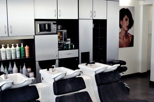 Bacs à shampoing et rangements, sous une affiche de coiffure