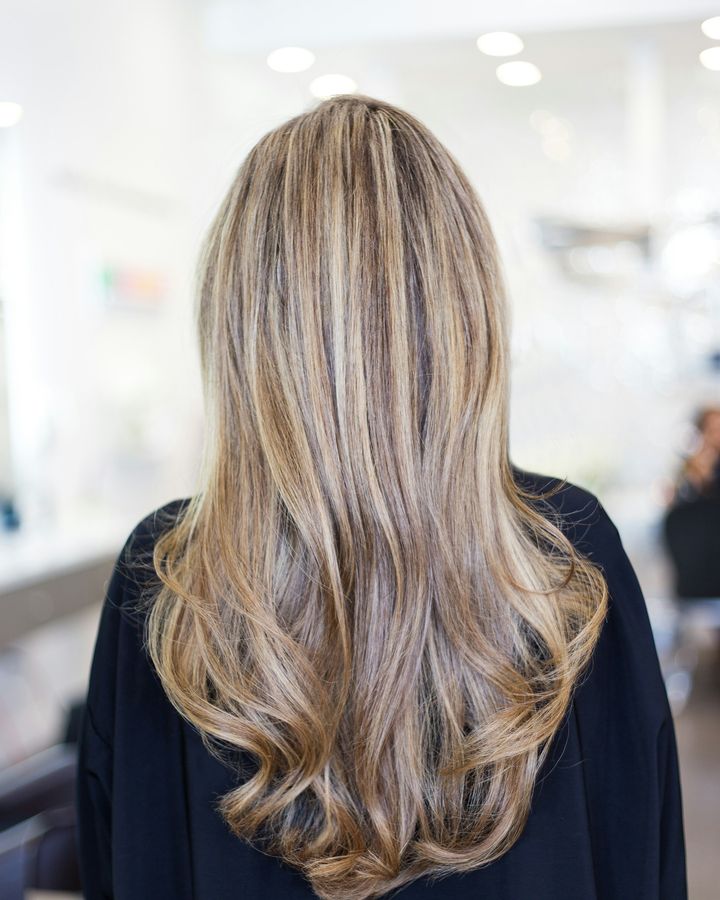 Longs cheveux blonds balayés, vus de dos, dans un salon de coiffure