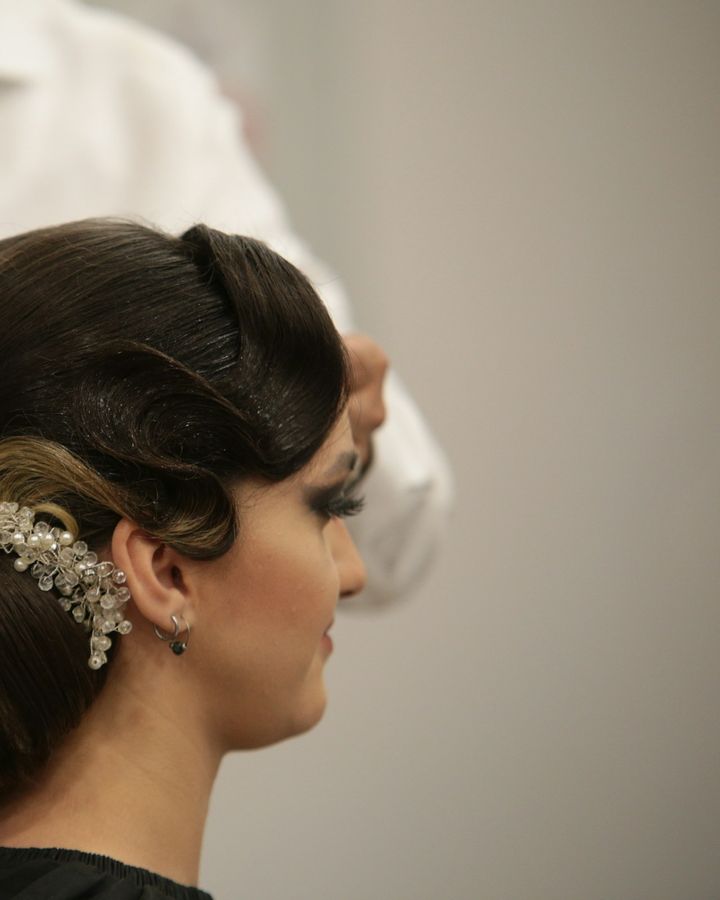 Coiffeur fixant à la laque un chignon orné d’un bijou de cheveux