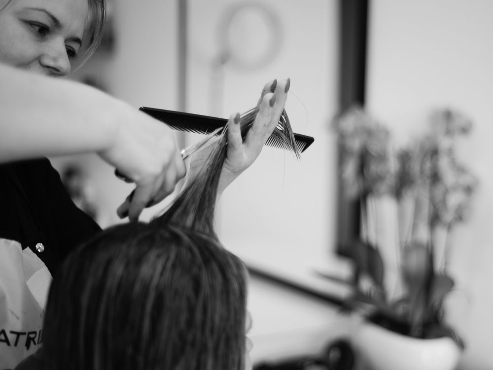 Coiffeuse coupant une mèche aux ciseaux, photo en noir et blanc